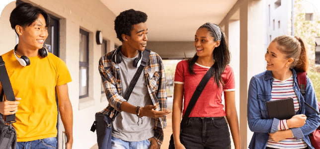 Four diverse high school students talking and walking down the hall