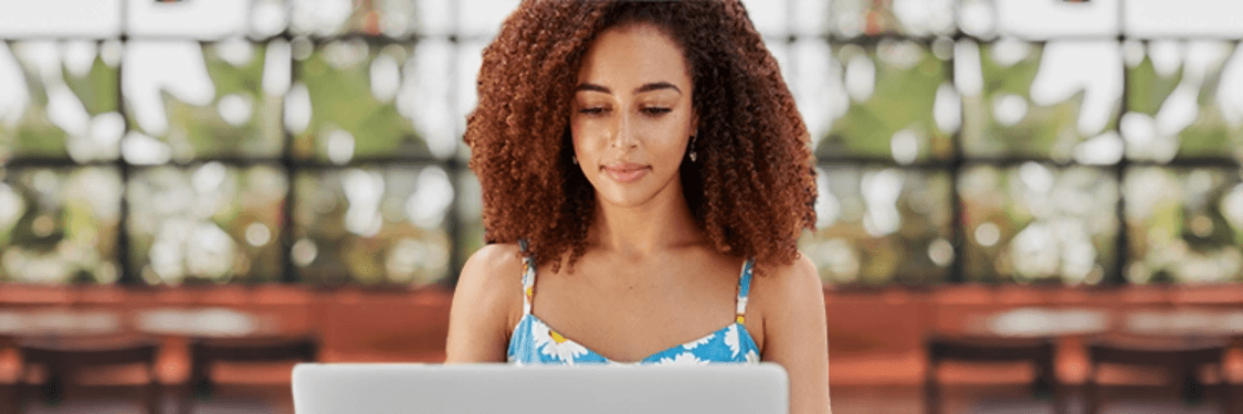 Woman with long hair typing on a laptop in a modern cafe